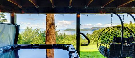 A vehicle with a view of a lake and mountains, a hanging chair, and a wooden structure.