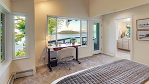 A bedroom with a bed, a desk, and a view of a lake. - Snow Goose Point: Stunning Views & New Hot Tub! (Anacortes)