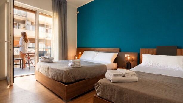 Habitación de hotel con dos camas, un balcón y vista al interior del edificio.