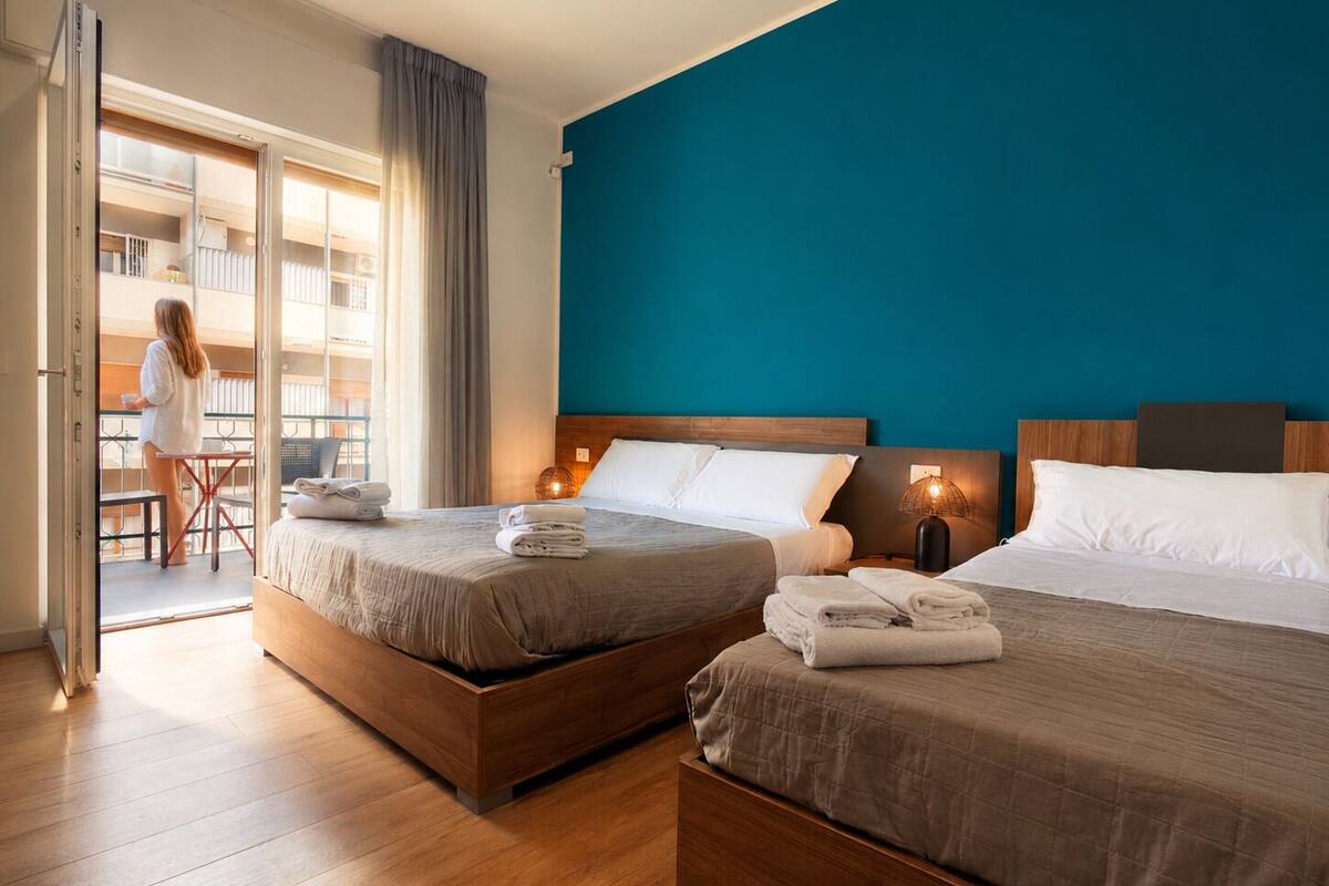 Habitación de hotel con dos camas, un balcón y vista al interior del edificio.
