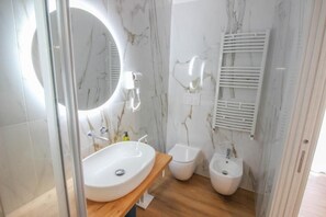 A modern bathroom with a large oval sink, a round mirror, a toilet, and a bidet. - Dadà - Luxury Suite (Bari)