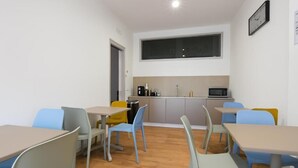 Una habitación con kitchenette, un ventanal grande y un reloj en la pared.