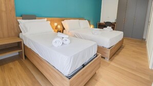 Habitación de hotel con dos camas, cabeceros de madera y una pared de acento color aguamarina.