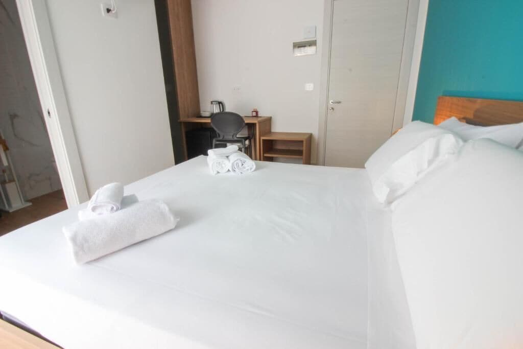 Une chambre d’hôtel avec un lit, un bureau, une chaise et une porte.