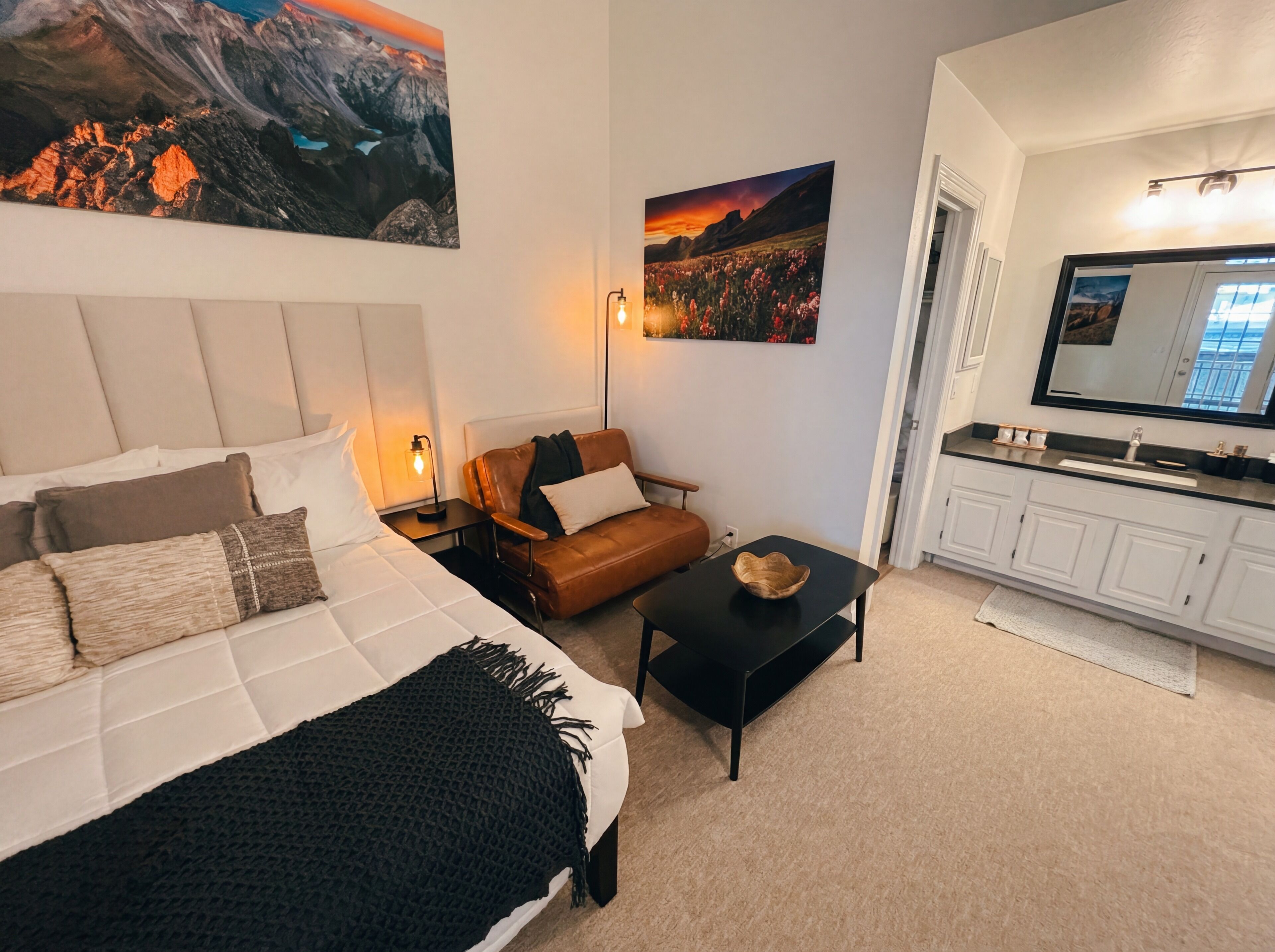 A bedroom with a bed, a sofa, a small table, and a TV in a modern apartment.