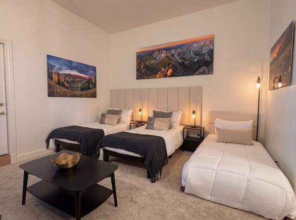 A hotel room with two beds, a sofa, a small table, and artwork on the walls.