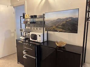 A kitchenette with a microwave, coffee maker, and storage drawers.