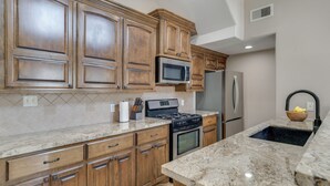 A kitchen with wooden cabinets, a stainless steel refrigerator, a microwave, a stove, and a granite countertop. - Boating, Fishing & Poolside Fun! Montgomery Escape (Montgomery)