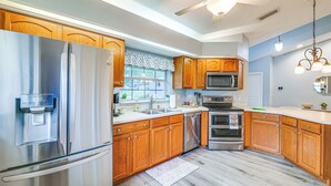 Una cocina con electrodomésticos de acero inoxidable, armarios de madera, un microondas y un ventilador de techo.