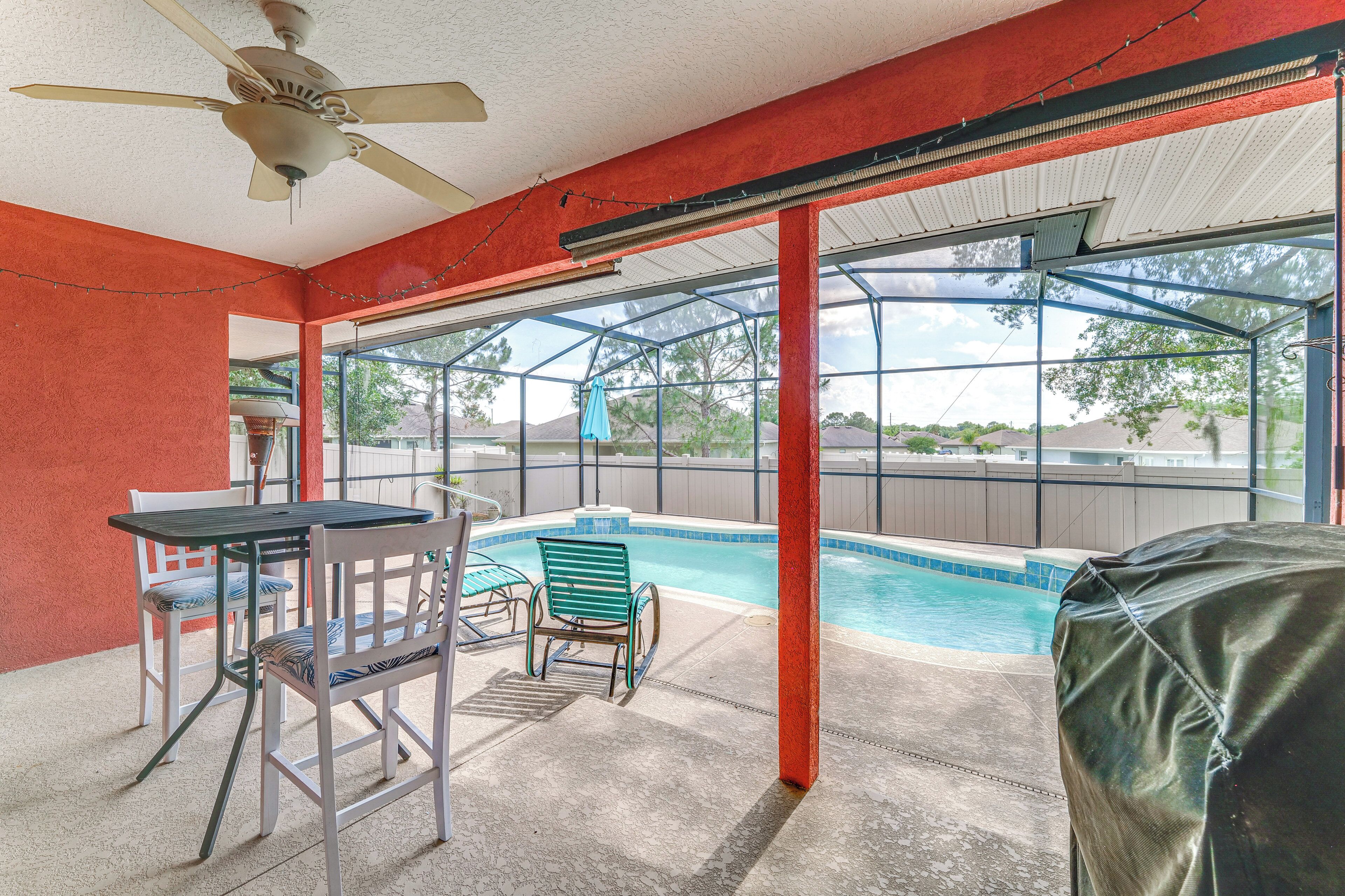 A covered outdoor area with a pool, chairs, and a table.