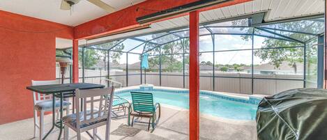 A covered outdoor area with a pool, chairs, and a table.