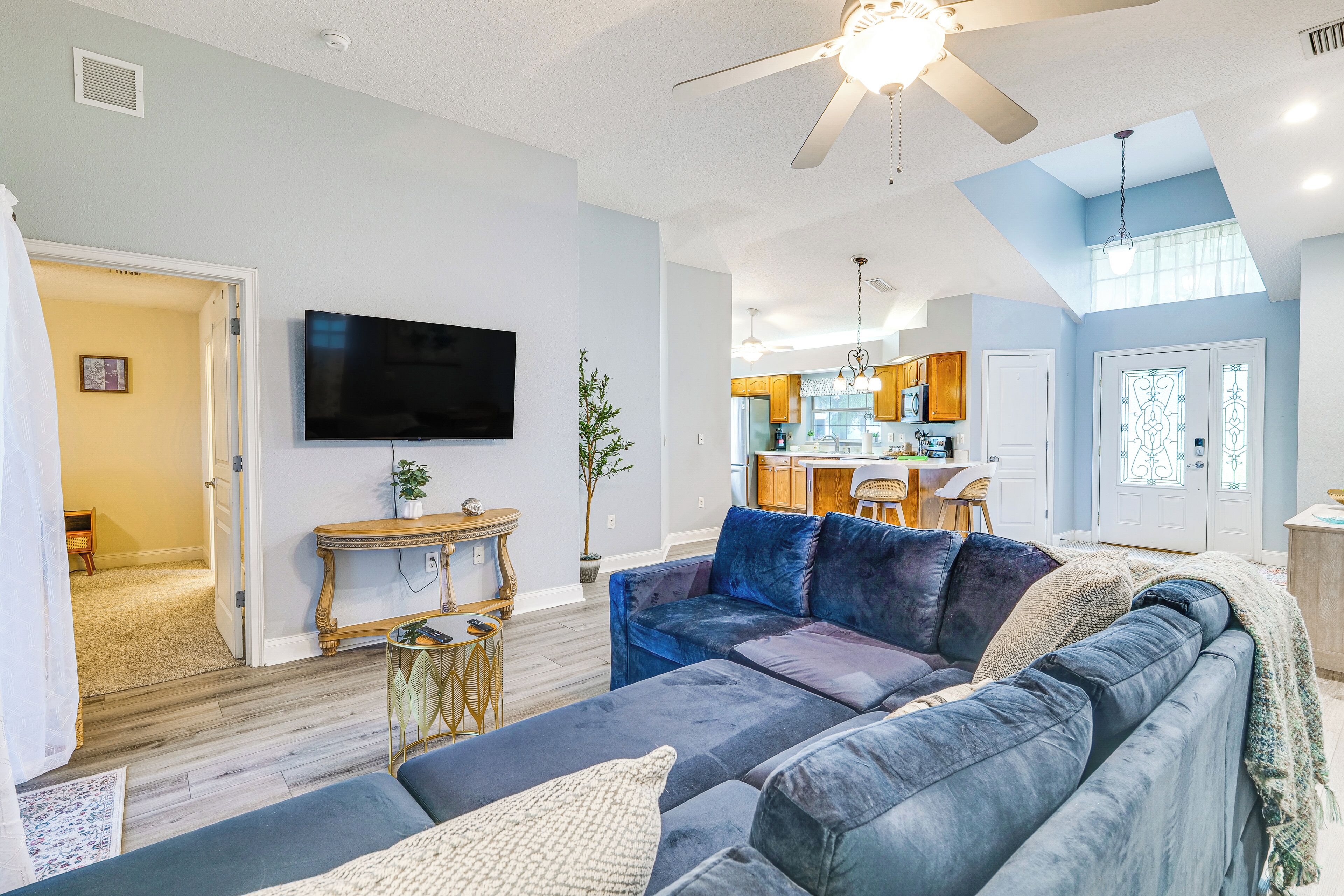 A living room with a large sofa, a flat-screen TV, and a ceiling fan.