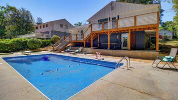 A residential property with a swimming pool, outdoor seating, and a covered patio area.