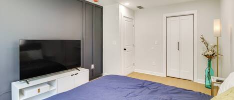 A bedroom with a bed, a TV, a ceiling fan, and a door.