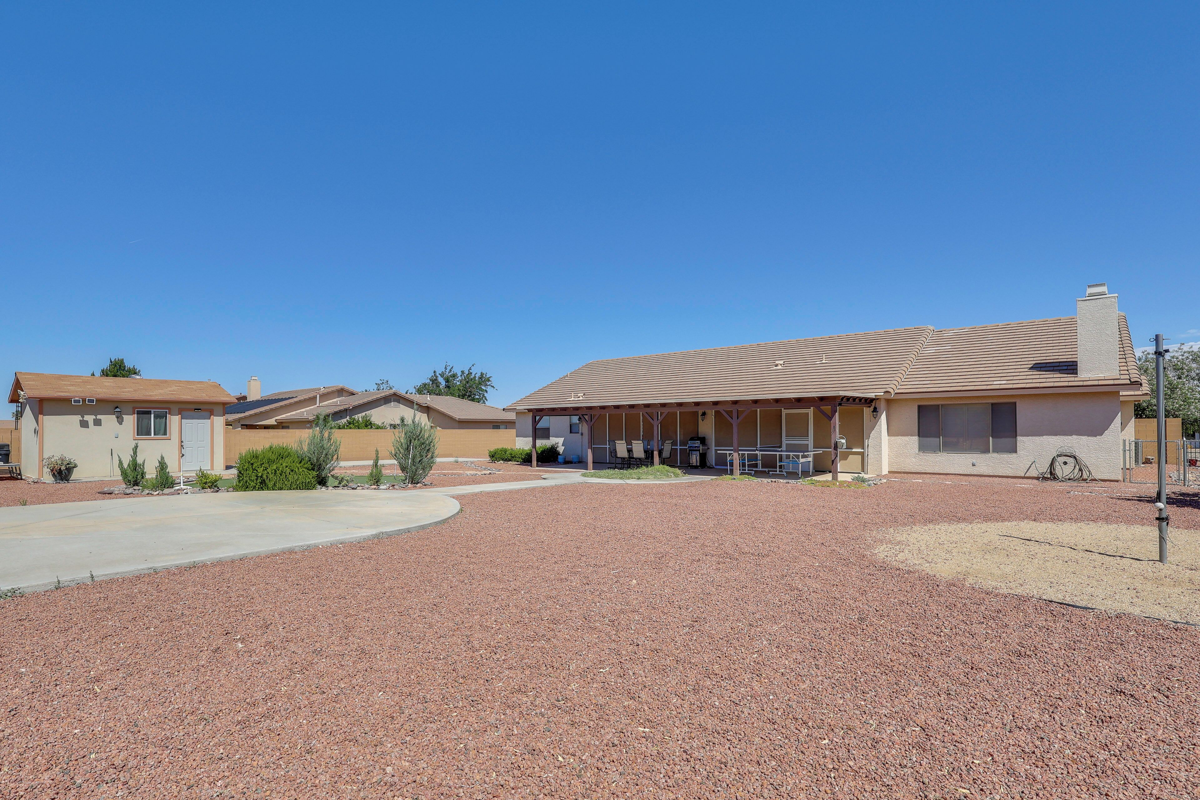 A residential area with houses, a covered patio, and a gravel driveway.