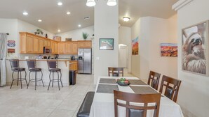 Una cocina moderna con armarios de madera, un refrigerador de acero inoxidable y un comedor con mesa y sillas.