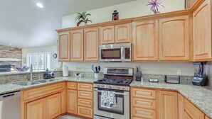 Una cocina con armarios de madera, electrodomésticos de acero inoxidable, encimeras de granito y lavavajillas.