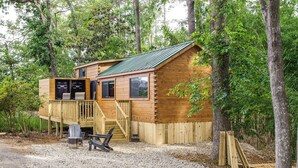 Une cabane en bois dotée d’une terrasse, d’un porche couvert et d’un sol en gravier.