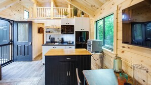 A cabin interior with a kitchen, dining area, and a balcony. - Tiny Cabin on Lake Murray, Private Dock for Boats (Chapin)