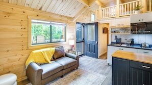 A wooden cabin interior with a sofa, kitchen, and a balcony. - Tiny Cabin on Lake Murray, Private Dock for Boats (Chapin)