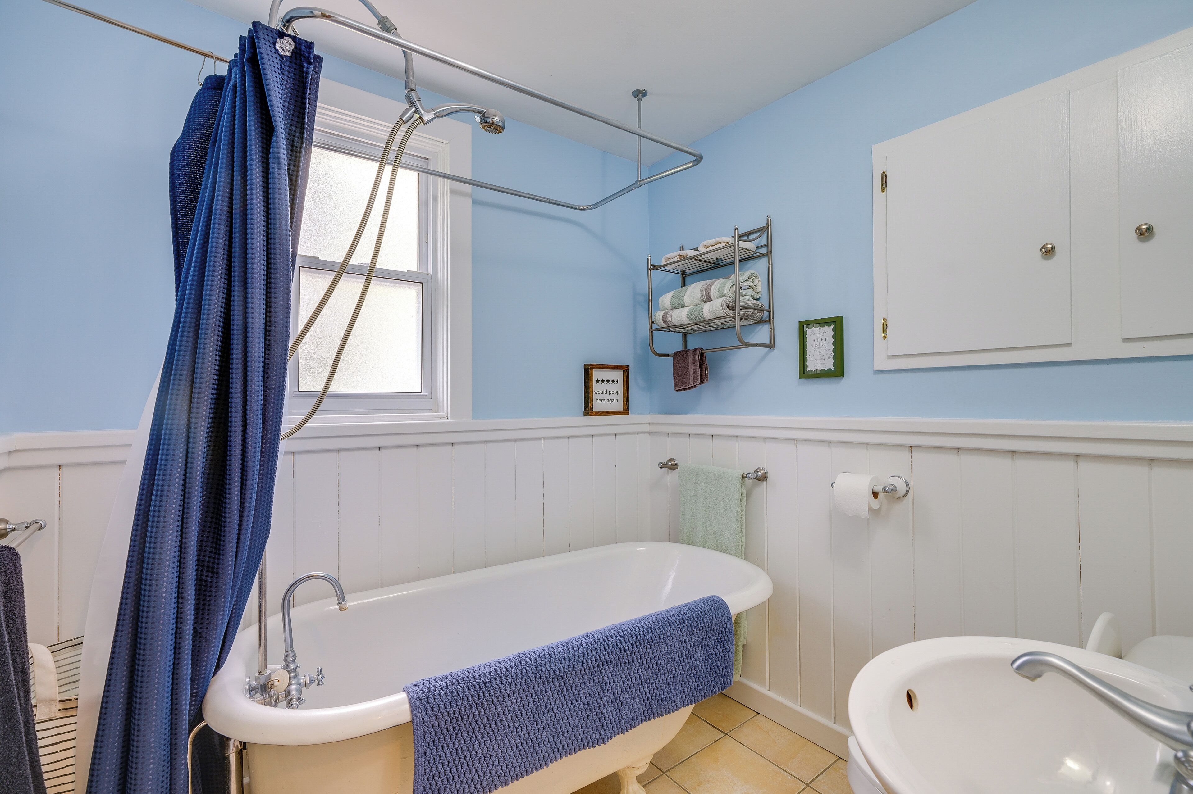 Ein Badezimmer mit einer Badewanne, einem Waschbecken, einem Handtuchhalter und einem Fenster.
