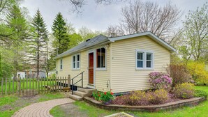 A single-story house with a front porch, a small garden with flowers, and a wooden fence. - 1/2 Mi to Lake & Dtwn! Elk Rapids 'cozy Cottage' (Elk Rapids)