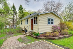 Ein eingeschossiges Haus mit einer Veranda, einem kleinen Garten mit Blumen und einem Holzzaun.