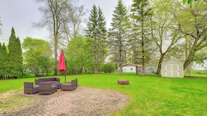 A circular brick patio with outdoor furniture, surrounded by a grassy area and trees. - 1/2 Mi to Lake & Dtwn! Elk Rapids 'cozy Cottage' (Elk Rapids)