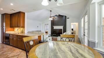 A spacious kitchen with wooden cabinets, a marble island, and a dining area with a round table.