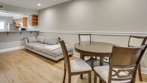 A dining area with a round table and four chairs, a sofa, and wooden cabinets. - Gateway to New Orleans! Modern Condo w/ Pool (Kenner)