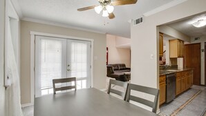 Un comedor con mesa y sillas, un ventilador de techo y vistas a una sala de estar y una cocina.