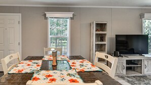 A dining area with a table set for four, a television, and a bookshelf.