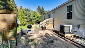 A residential property with a deck, outdoor grill, satellite dish, and an air conditioning unit.