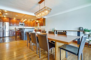A modern kitchen with wooden cabinets, stainless steel appliances, and a dining area with a wooden table and chairs. - White Bear Lake Lakehouse w/ Dock & Paddleboards (White Bear Lake)
