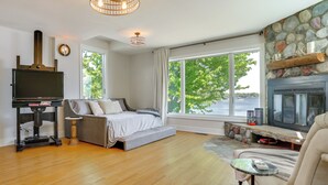 A bedroom with a bed, a TV, a fireplace, and a large window. - White Bear Lake Lakehouse w/ Dock & Paddleboards (White Bear Lake)