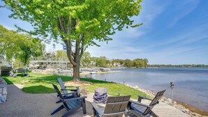 A lakeside deck with Adirondack chairs, a picnic table, and a tree providing shade. - White Bear Lake Lakehouse w/ Dock & Paddleboards (White Bear Lake)