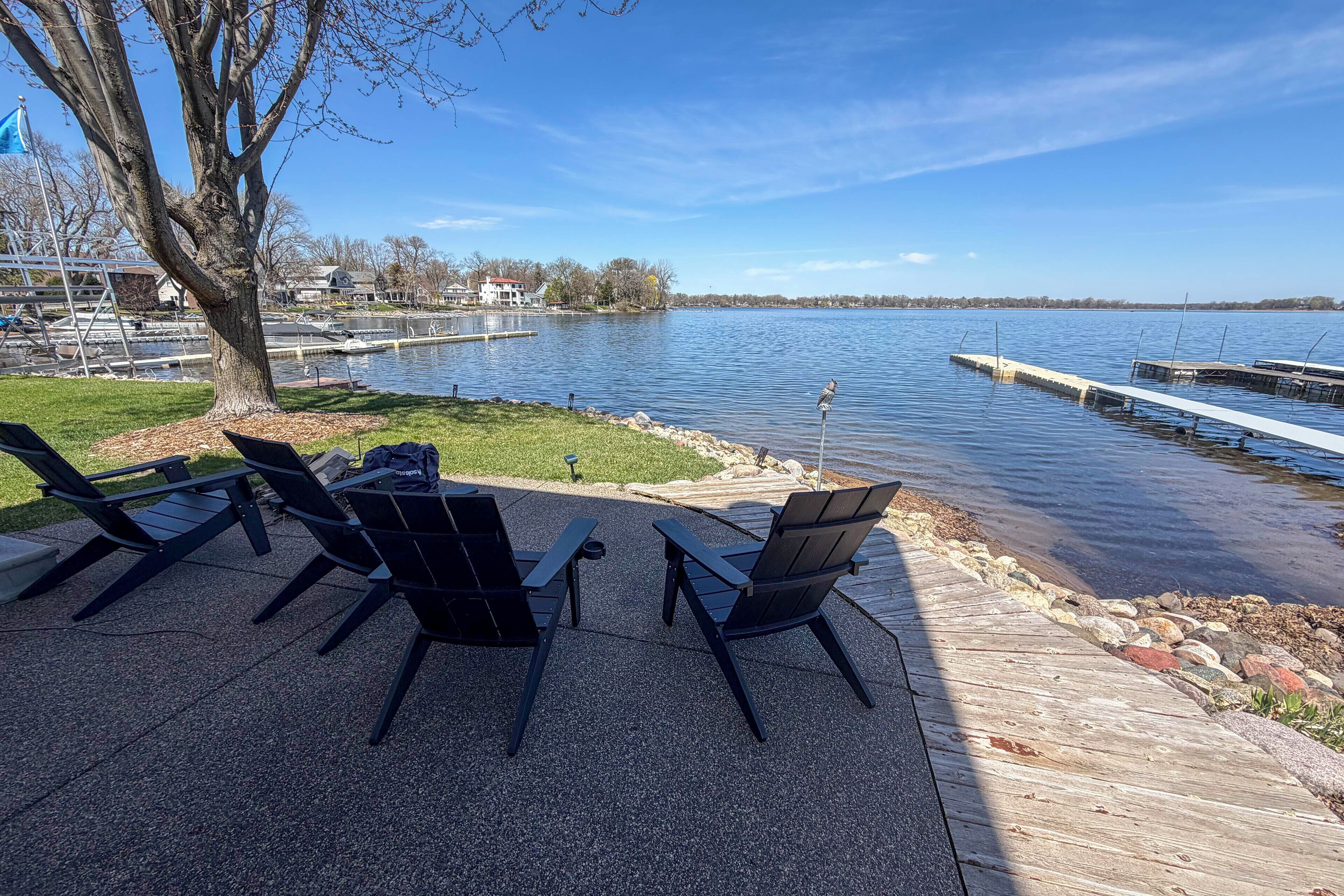 A deck with chairs overlooking a lake, dock, and distant buildings.