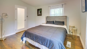 Ein Schlafzimmer mit einem Bett, einer Stehlampe, einem Fenster mit Vorhängen, einer Heizung und einem Bild an der Wand.