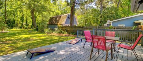 A wooden deck with outdoor furniture, a grassy yard, and a house in the background.