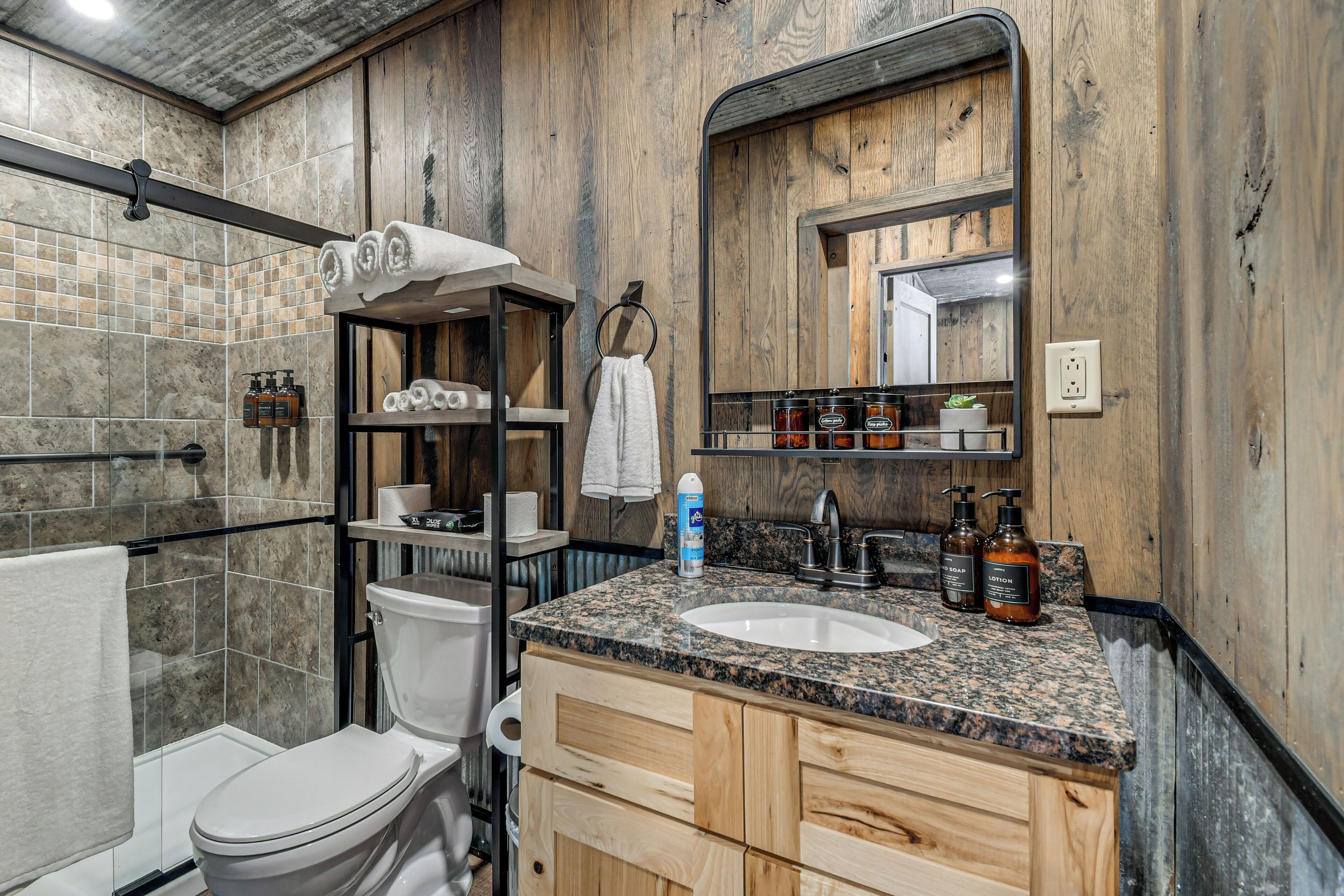 A bathroom with a toilet, sink, wooden cabinets, a towel rack, and a mirror.