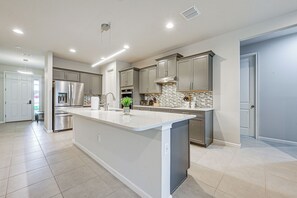 Uma cozinha moderna com uma ilha grande, eletrodomésticos de aço inoxidável e piso ladrilhado.