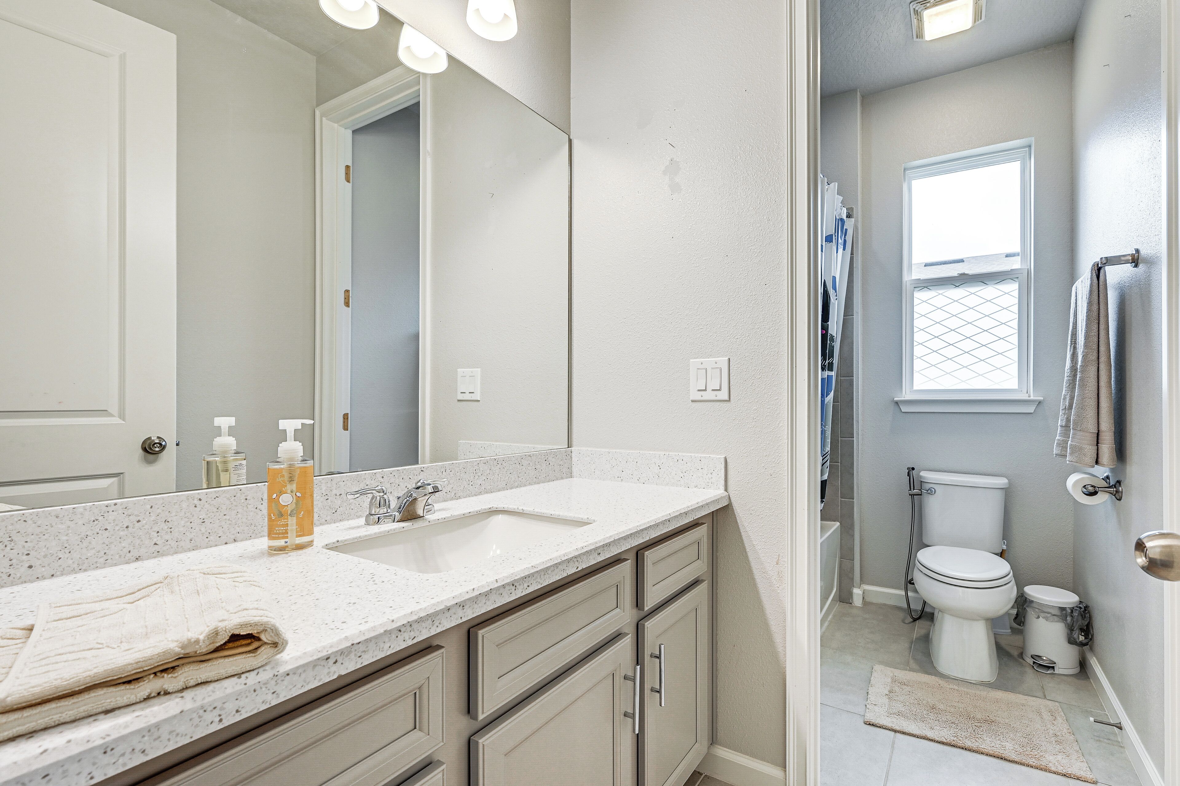A bathroom with a white sink, mirror, and toilet.