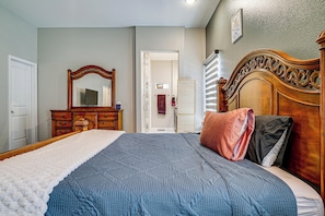 A bedroom with a bed, dresser, mirror, and a door leading to another room. - Family Home w/ Yard in El Paso Area, Pets Welcome! (Santa Teresa)