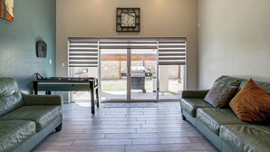 Een woonkamer met een bank, een salontafel en een grill buiten de schuifdeur.