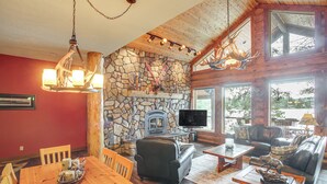 A cozy cabin interior with a stone fireplace, leather furniture, and a television. - Dock, Decks & Epic View! Sacheen Lake Family Cabin (Newport)