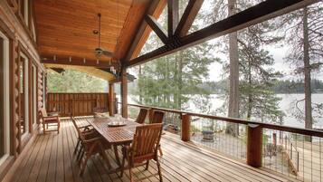 Terraza de madera con mesa y sillas, con vistas a un lago.