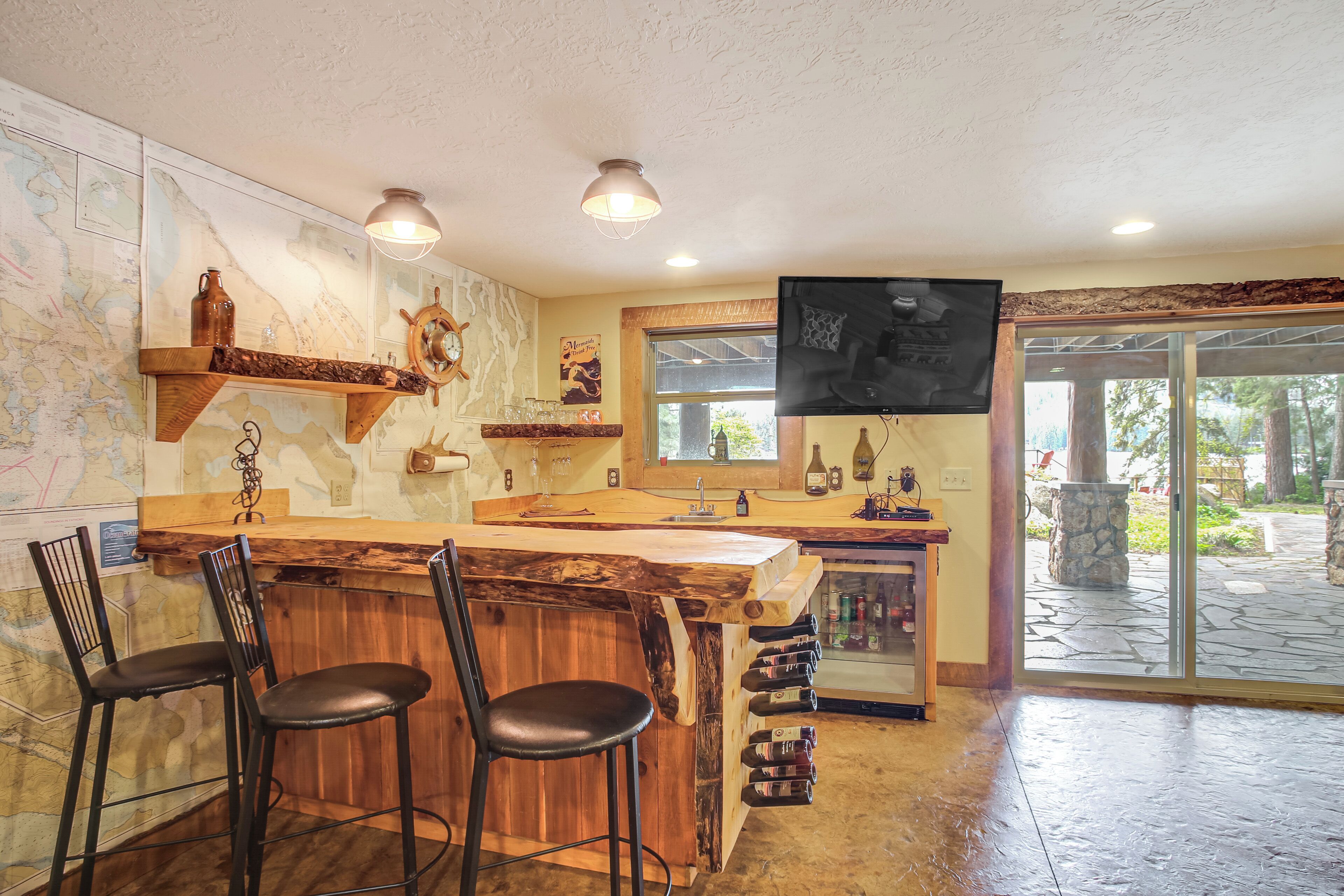 A bar area with wooden bar top, stools, and a wine rack.