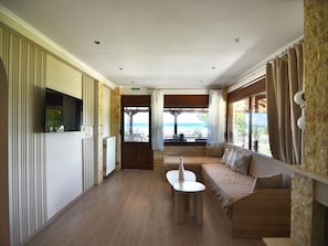 Quarto de hotel moderno com sofá, uma mesinha e televisão.