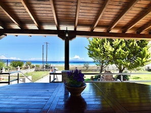 Una terraza de madera con vista al océano y un árbol.