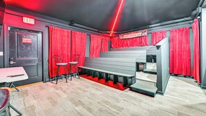 Een theater met rode gordijnen, een nooduitgang en een zitgedeelte met banken.